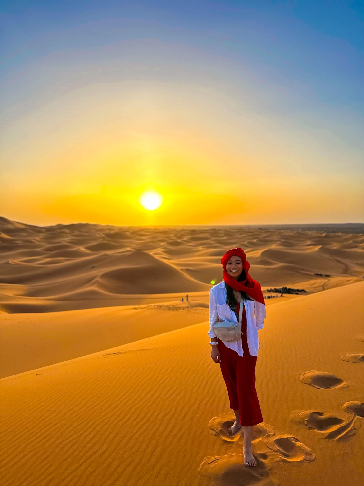 Woman in red clothes in sahara moroco solo sunset